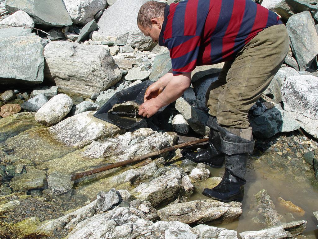 Руками из образовавшейся после работы ломом трещины золотоносная порода кидается на лоток дальше в ведро и уносится на проходнушку